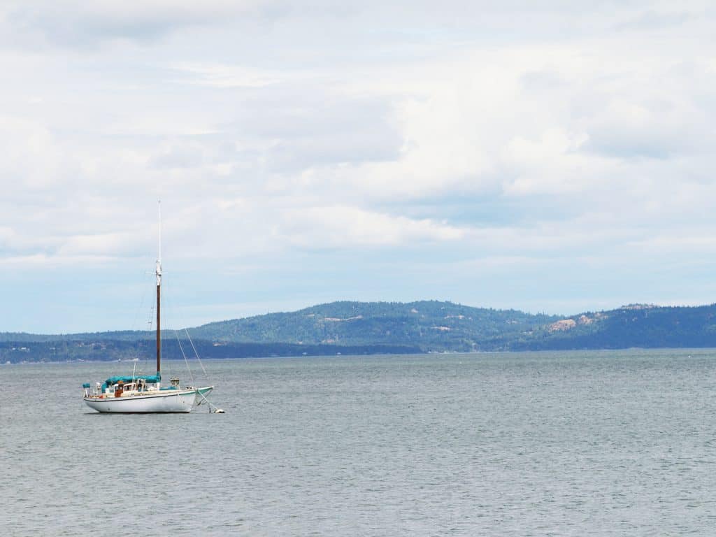A peaceful ocean view with a sailboat anchored near the shore, capturing the serene and breezy essence of coastal living.
