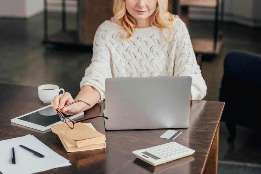 a Woman on her computer working on bills and researching online, perhaps to purchase a home