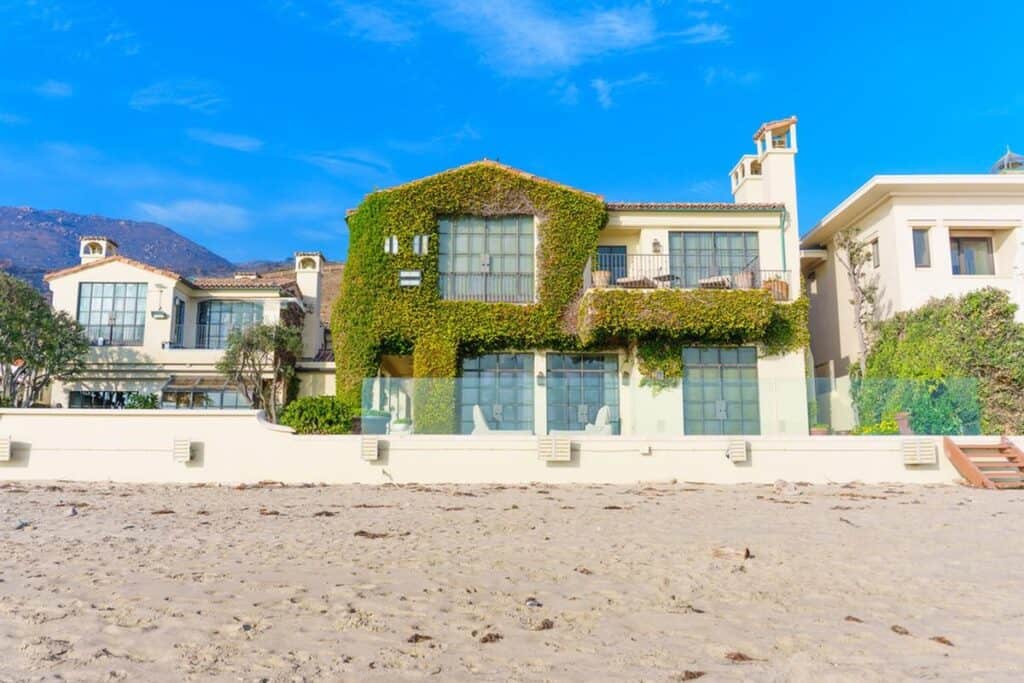 A beach house with a large pool and a large driveway in Malibu, California, one of the best locations for those seeking coastal living.
