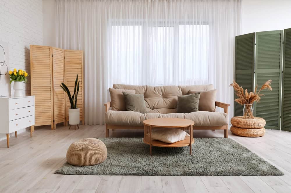 Bright living room with beige sofa, green plants, and natural accents.